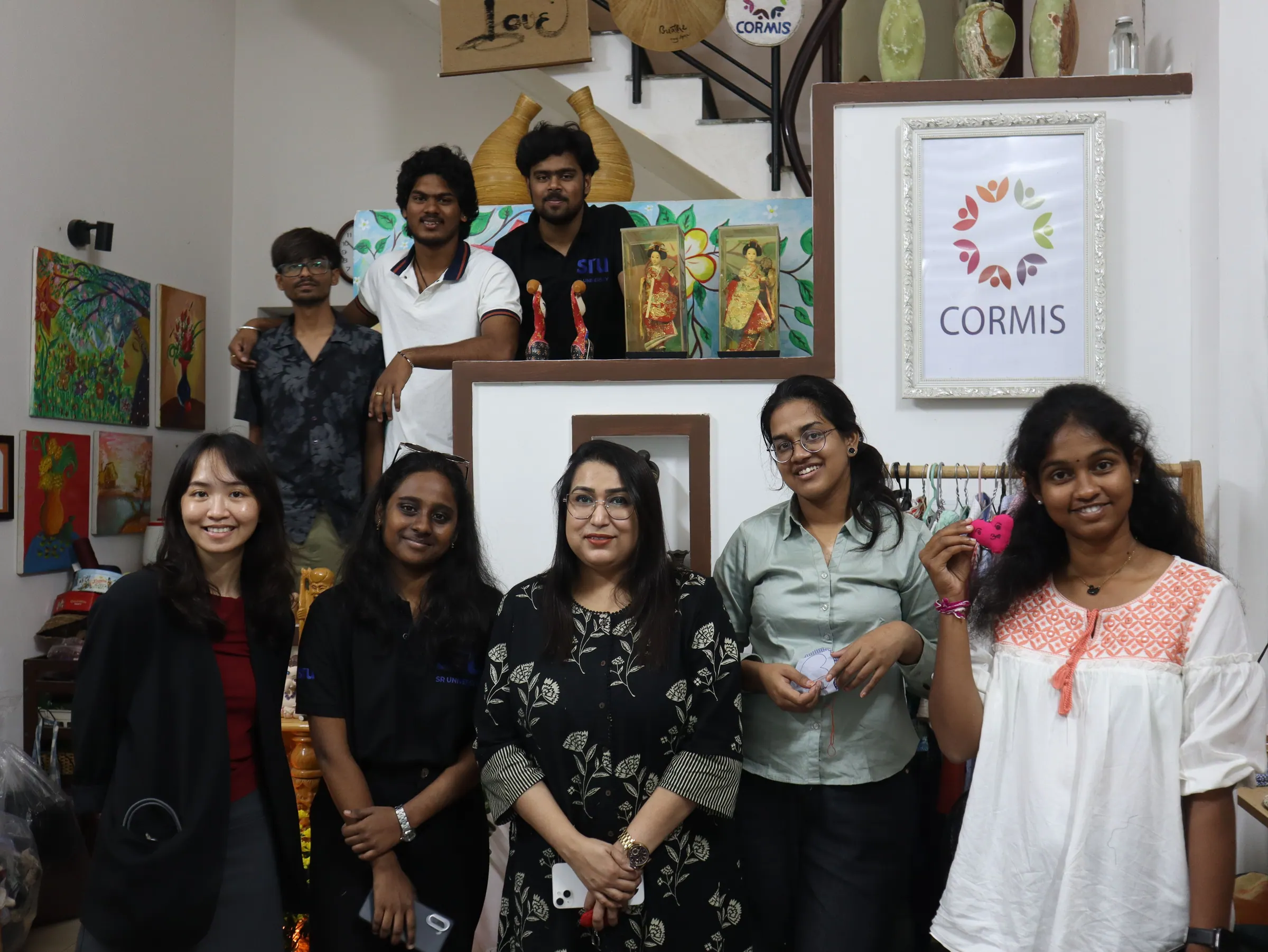 The group posing together in front of a CORMIS sign